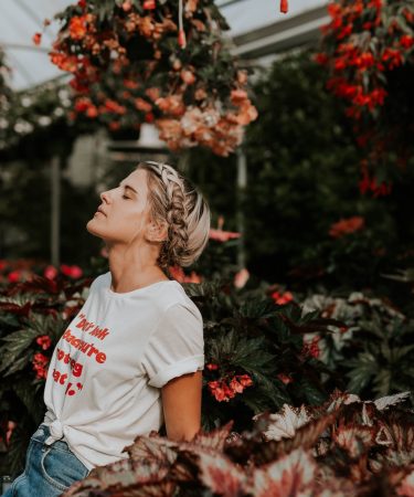 woman wearing white shirt standing near the flower