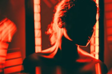 unrecognizable woman full body red light therapy dark room 1200x628 facebook.jpg